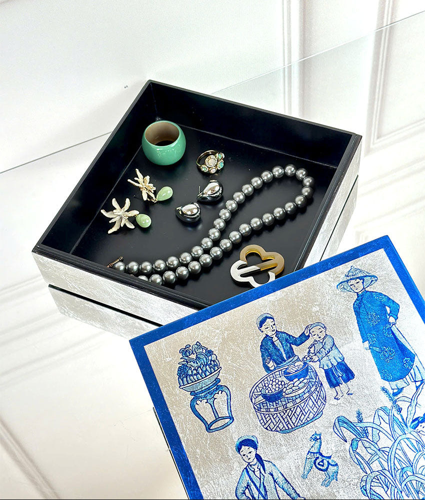 Jewelry set including a necklace, earrings, and a lock on a black tray with a decorative lacquer box featuring blue and silver designs.