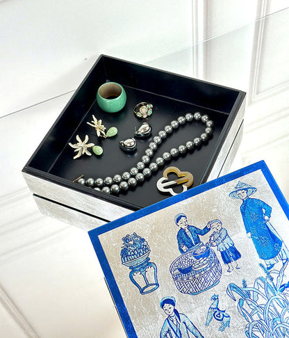 Jewelry set including a necklace, earrings, and a lock on a black tray with a decorative lacquer box featuring blue and silver designs.