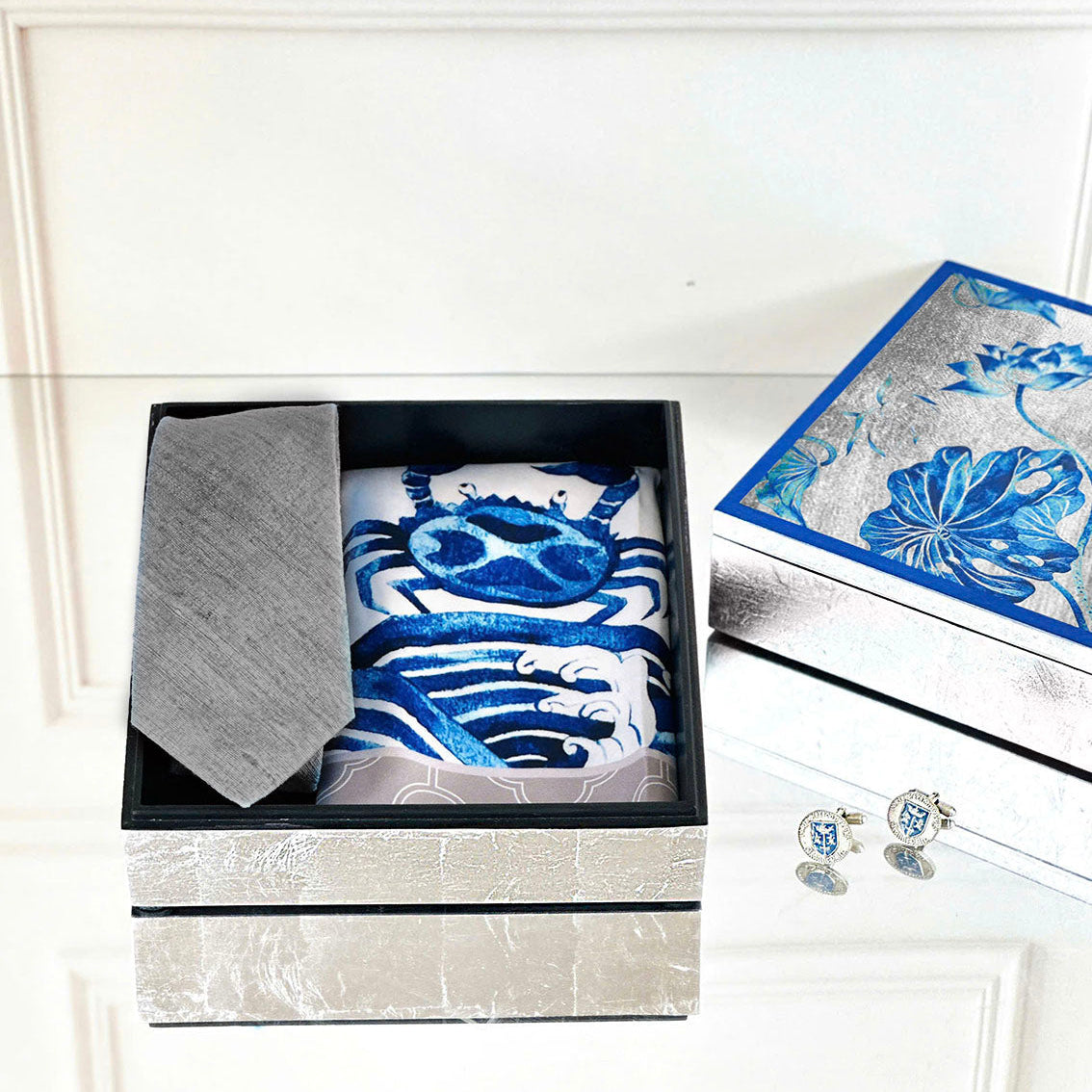 Set of blue and white patterned fabric items in a box with a matching box and cufflinks on a white surface.